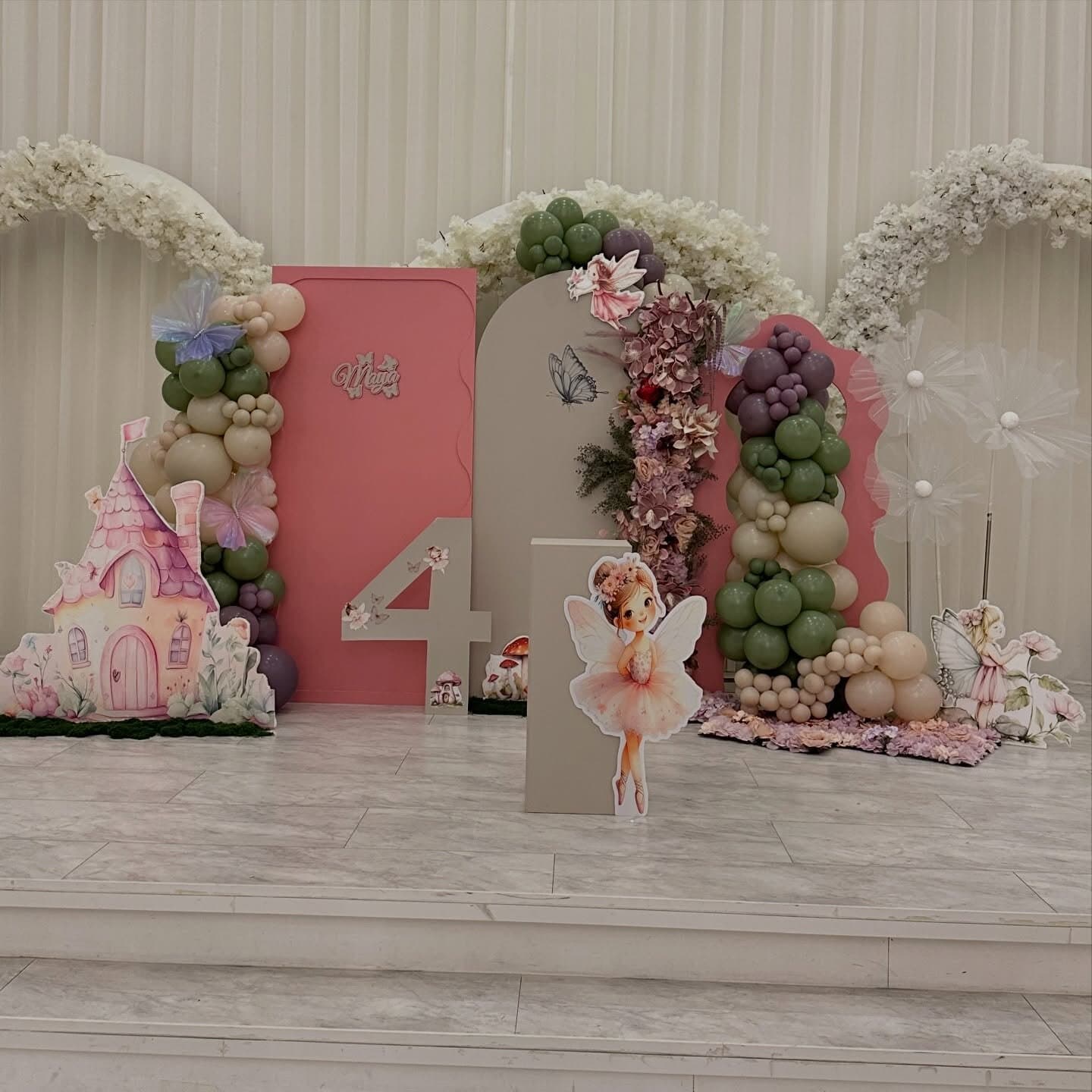 Fourth birthday fairy garden set with a soft sage and cream balloon garland, florals and themed props