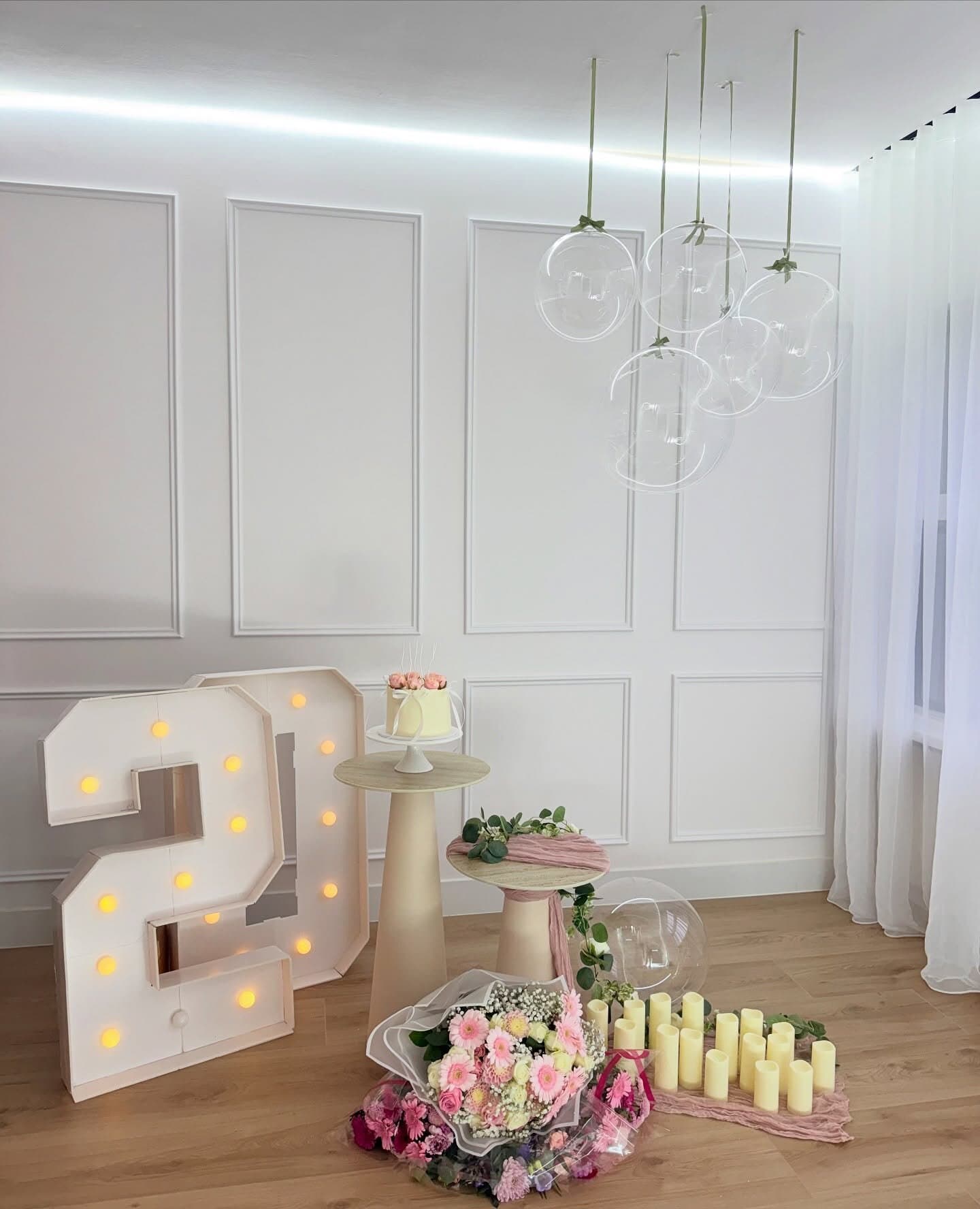 Transparent orbs and illuminated marquee numerals with pink gerbera bouquets — organic balloon styling for a milestone birthday